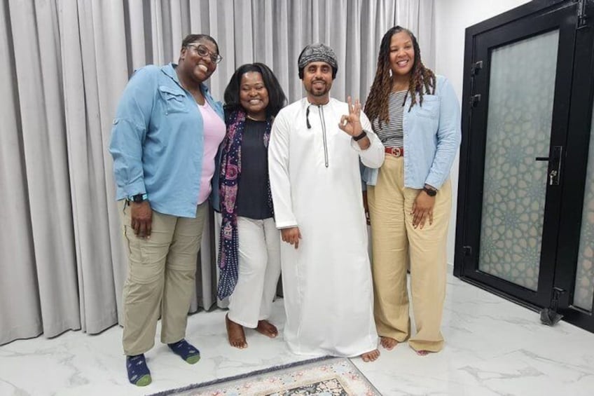 Four people standing indoors with a curtain backdrop and a door with a patterned glass panel. 5