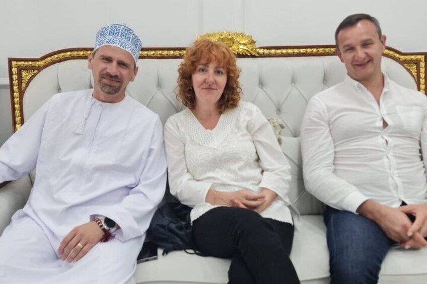 Three people sitting on a white sofa with a gold frame. 2