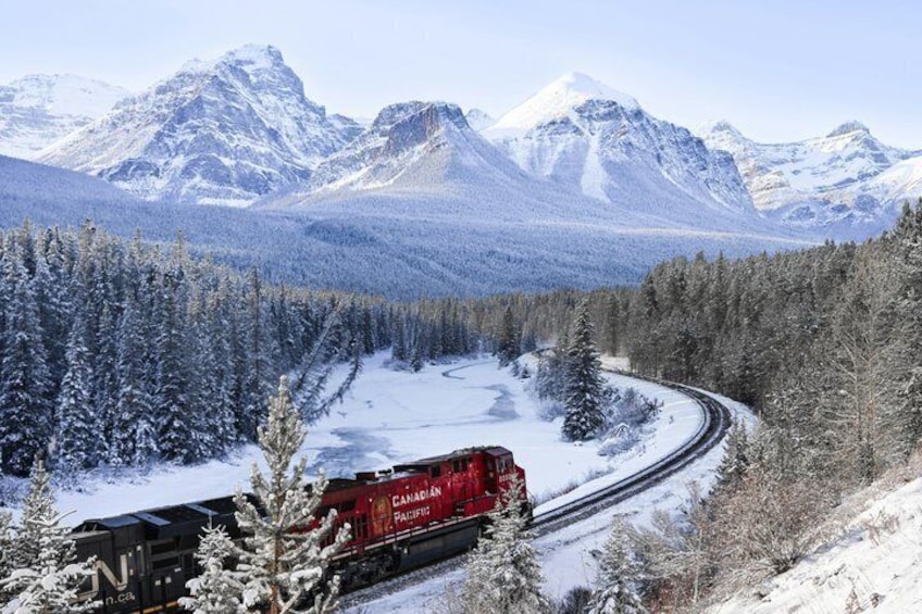 A red Canadian Pacific train on a snowy mountain track surrounded by snow-covered trees and mountains. 3