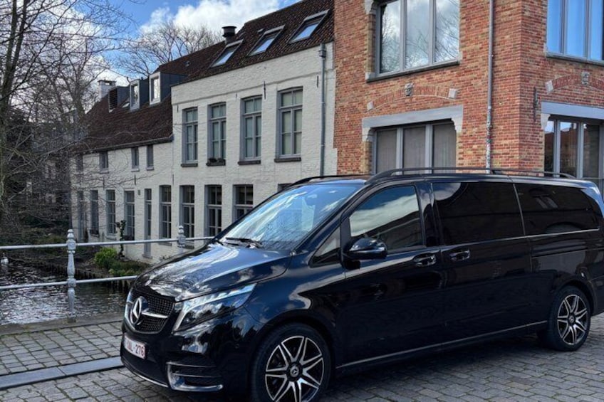 A black Mercedes-Benz C-Class station wagon parked on a cobblestone street in front of a brick building with multiple windows. 5