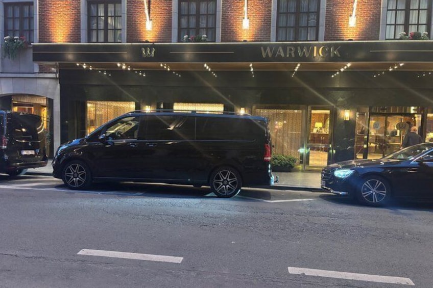 A black van parked in front of a building with the sign 'WARWICK' and a black car parked to the right. 3