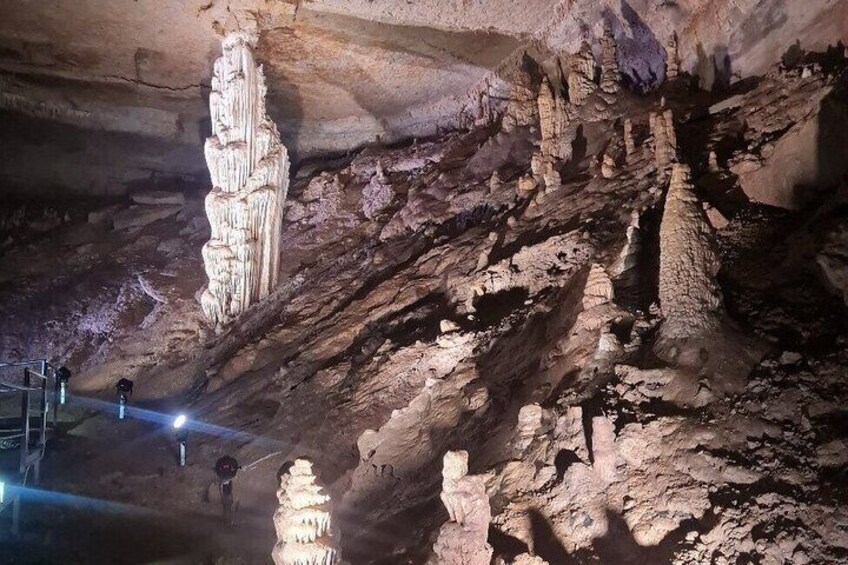 A cave with stalactites and stalagmites, a person climbing, and a light source. 2