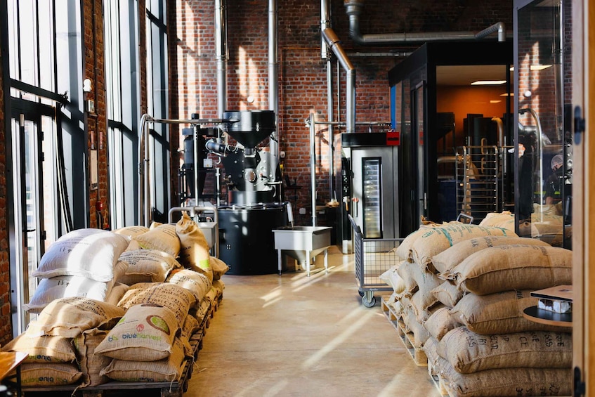 A warehouse with industrial equipment, sacks of grain, and a brick wall. 5