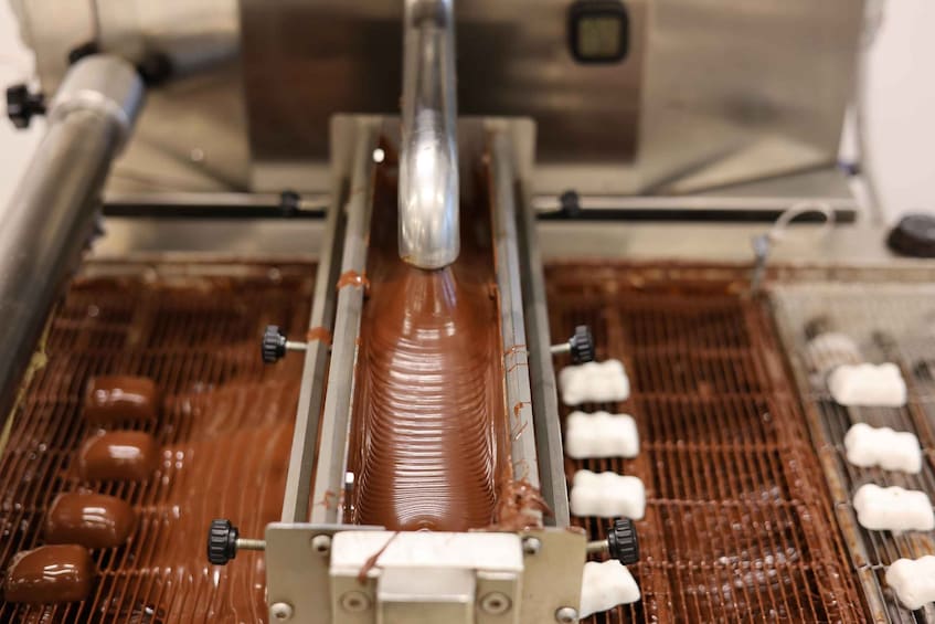 A chocolate tempering machine with a smooth, glossy chocolate bar being processed. 2
