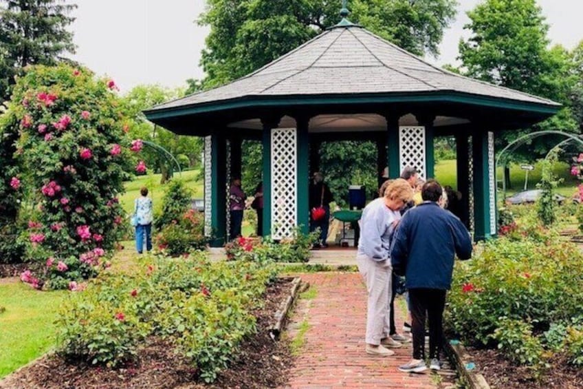 A gazebo surrounded by a garden with roses and a pathway. 2