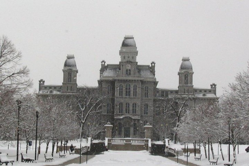 A large, historic building with a symmetrical facade, snow-covered trees, and a clear sky. 3