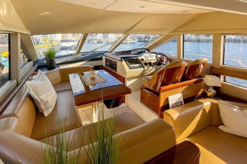 A yacht interior with leather seating, a wooden table, and a steering wheel. 4