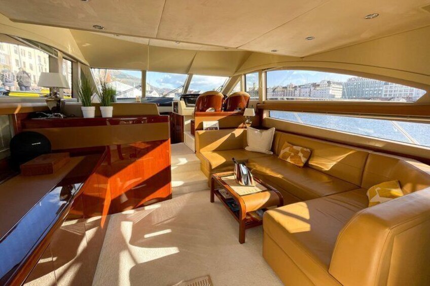 A yacht interior with a sofa, coffee table, and a view of the water outside. 3
