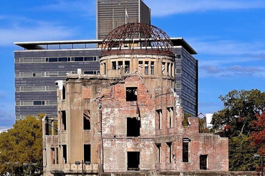 A dilapidated building with a dome structure, surrounded by modern high-rise buildings. 1