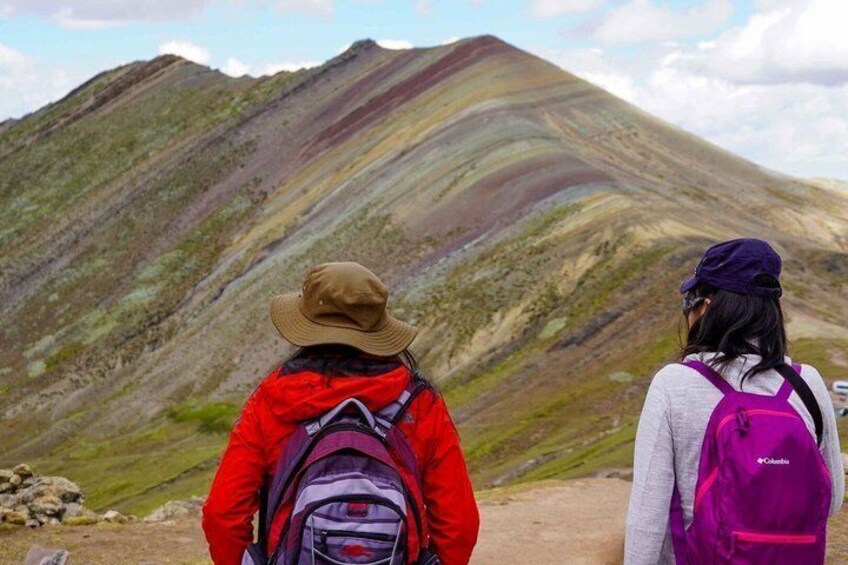Two hikers with backpacks facing a mountain. 3