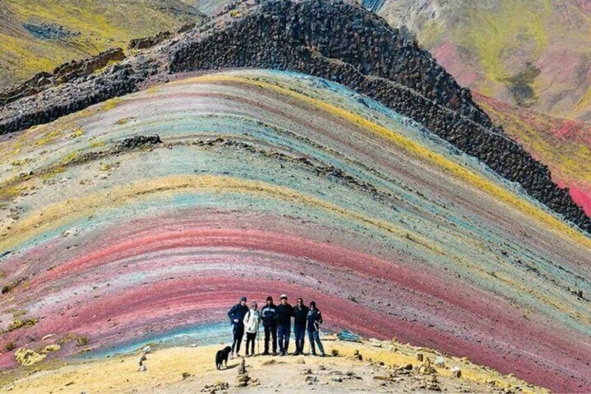 A multicolored geological formation with people standing on a flat area at its base. 1