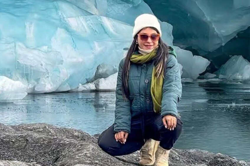 A person sitting on a rock with icebergs in the background. 1