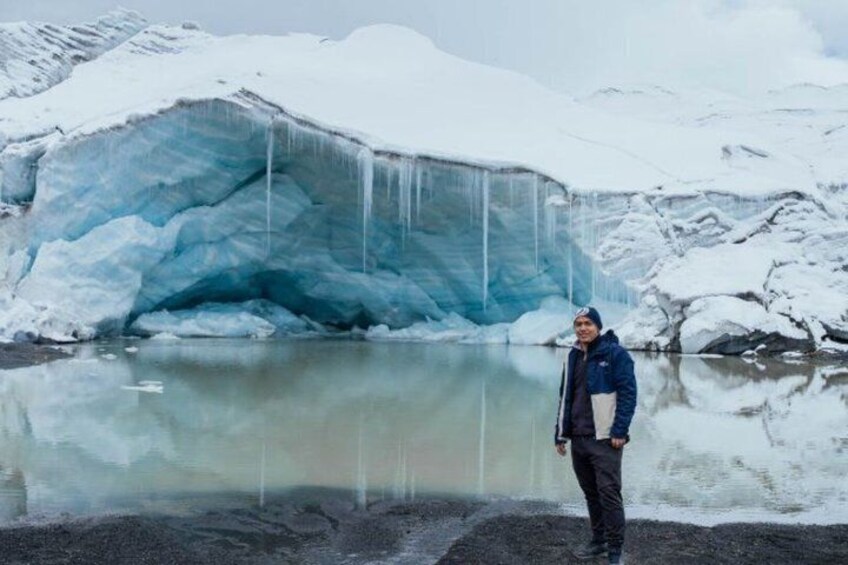 A glacier with a person standing in front of it. 4