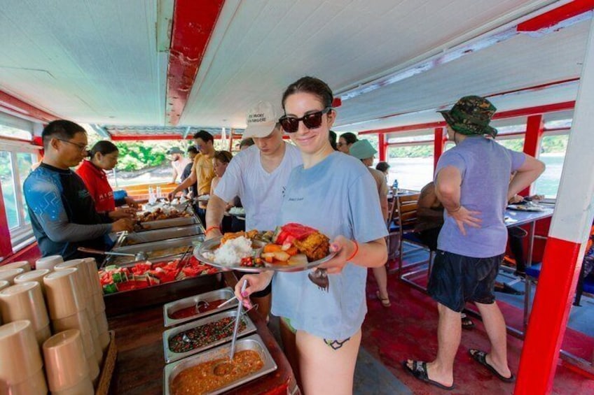 A buffet setup with food containers and people serving and eating. 2