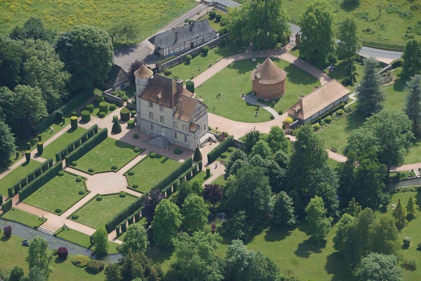An aerial view of a historic estate with a large manor house, a round tower, and meticulously maintained gardens. 5