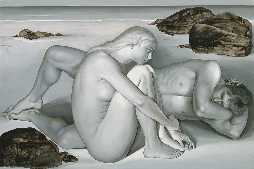 A sculpture of two figures on a beach with rocks. 4