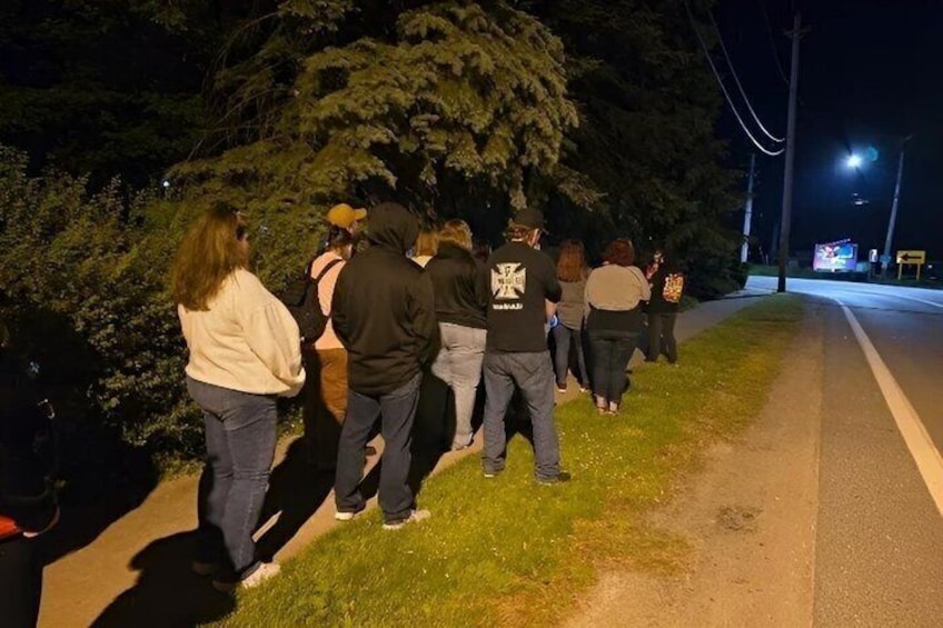 A group of people walking along a sidewalk at night. 4