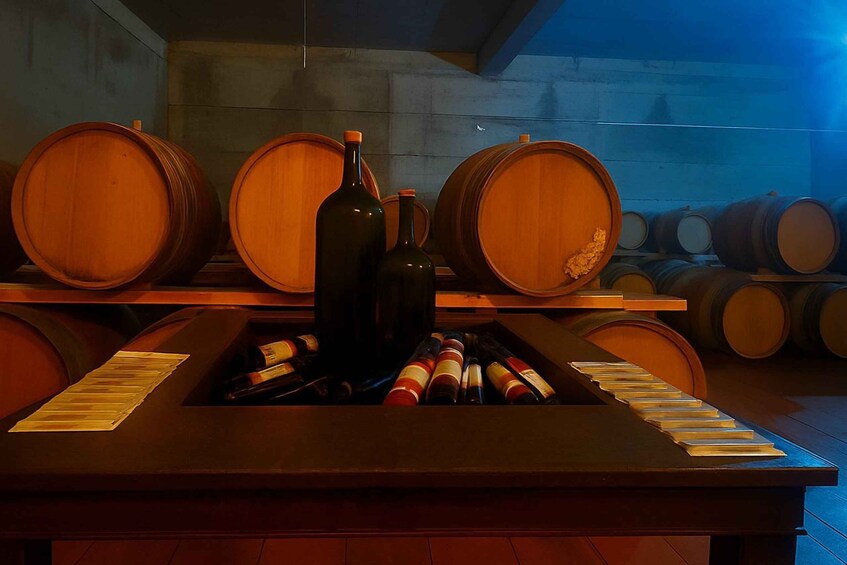 Wooden wine barrels and bottles in a dimly lit cellar. 5
