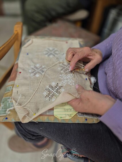 A person sewing a lace pattern onto a fabric. 4