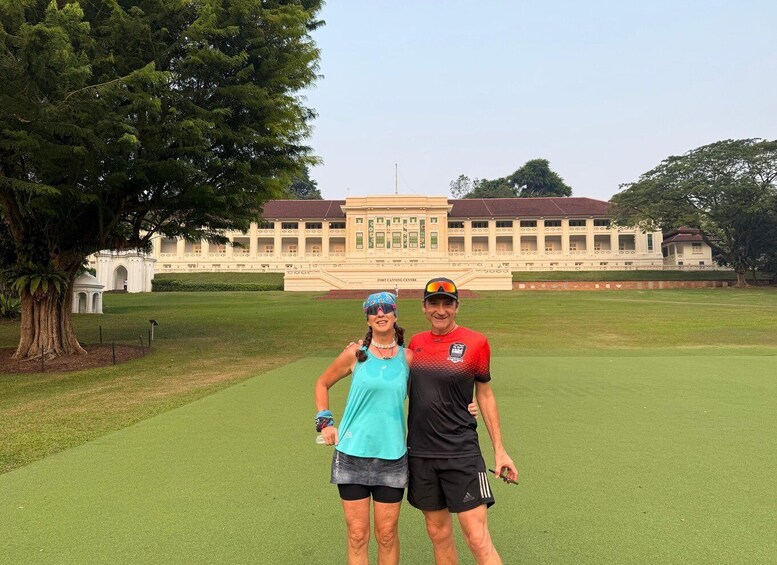 Two people standing on a golf course with a large building in the background. 4