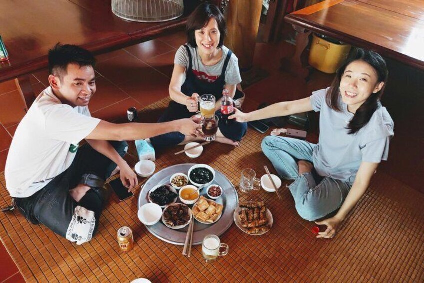Three people sitting on a tatami mat floor, toasting with drinks. 3