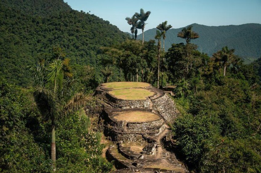 A stone structure with a circular platform surrounded by dense forest and hills. 5
