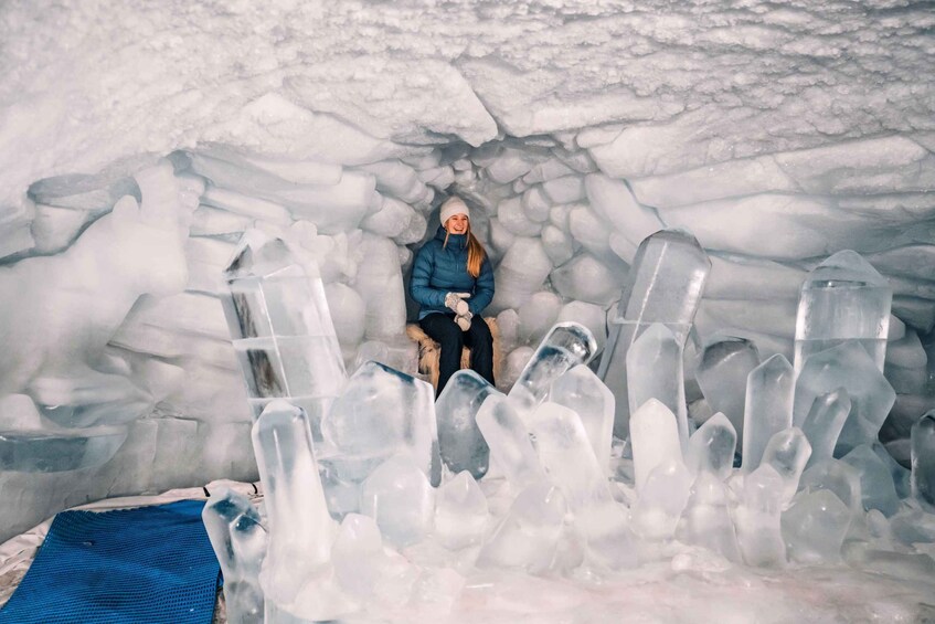 A person sitting in an ice cave surrounded by ice formations. 4