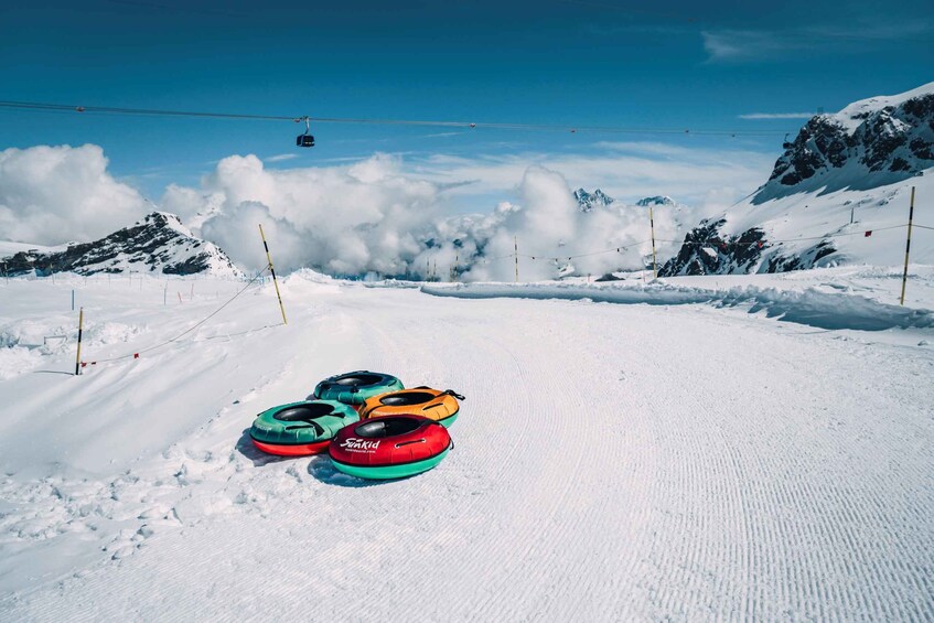 A snowy mountain landscape with a ski lift in the background and colorful inflatable rings on the snow. 5