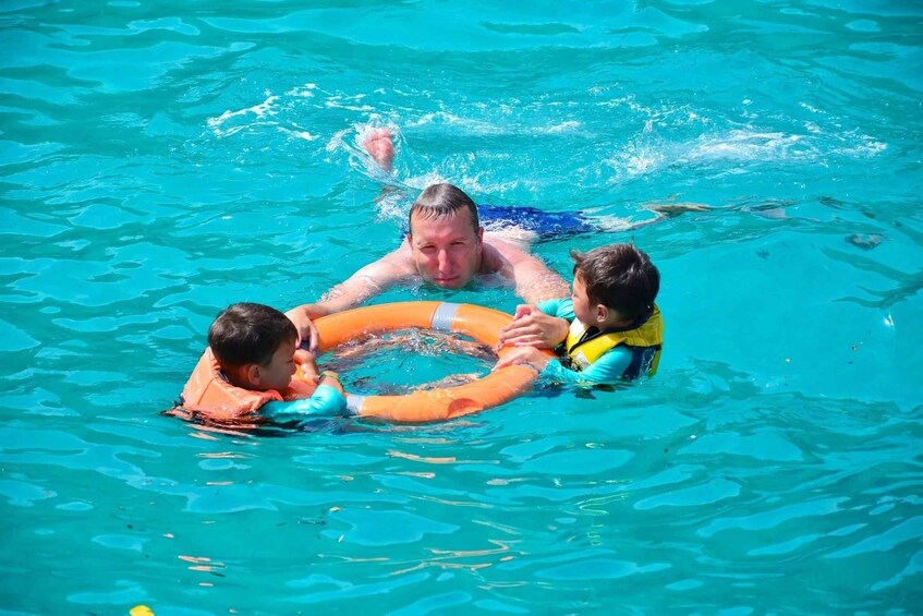 A man and two children in a swimming pool with a floating ring. 2
