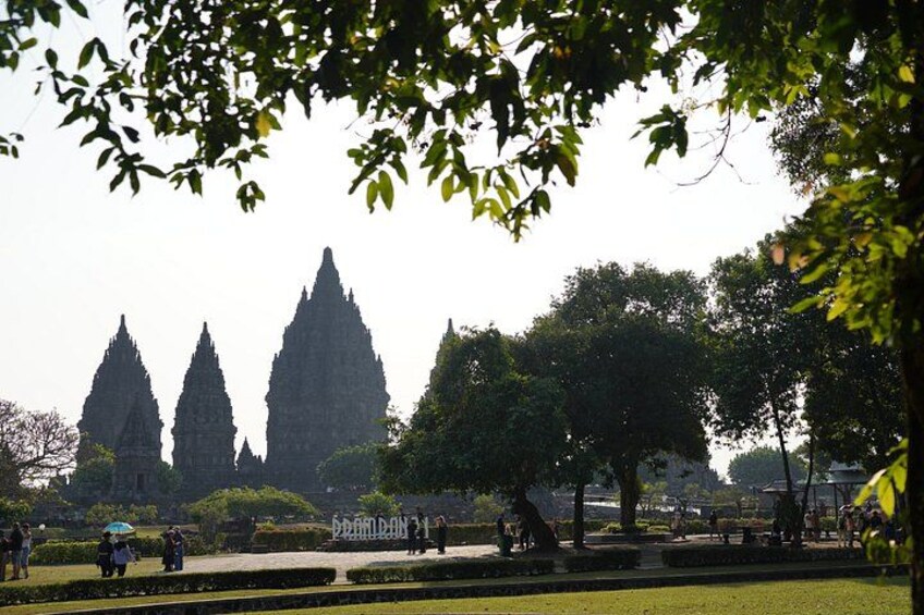 A park with trees and a distant view of three tall, pointed structures. 2