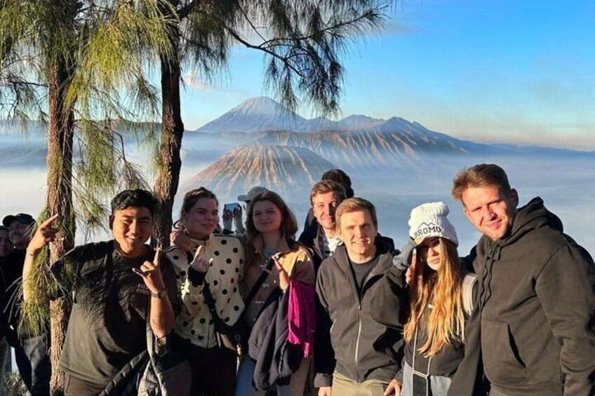 A group of people standing in a forested area with a mountain in the background. 3