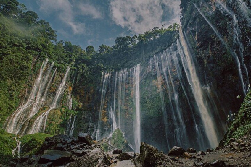 A multi-tiered waterfall surrounded by lush greenery. 1