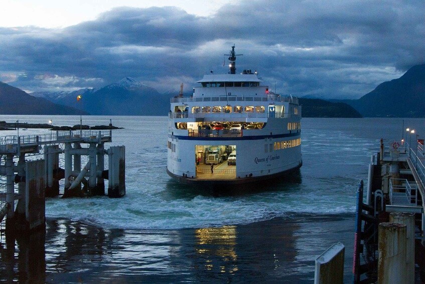 A ferry named 'Queen of the Skies' docked at a pier with mountains in the background. 5