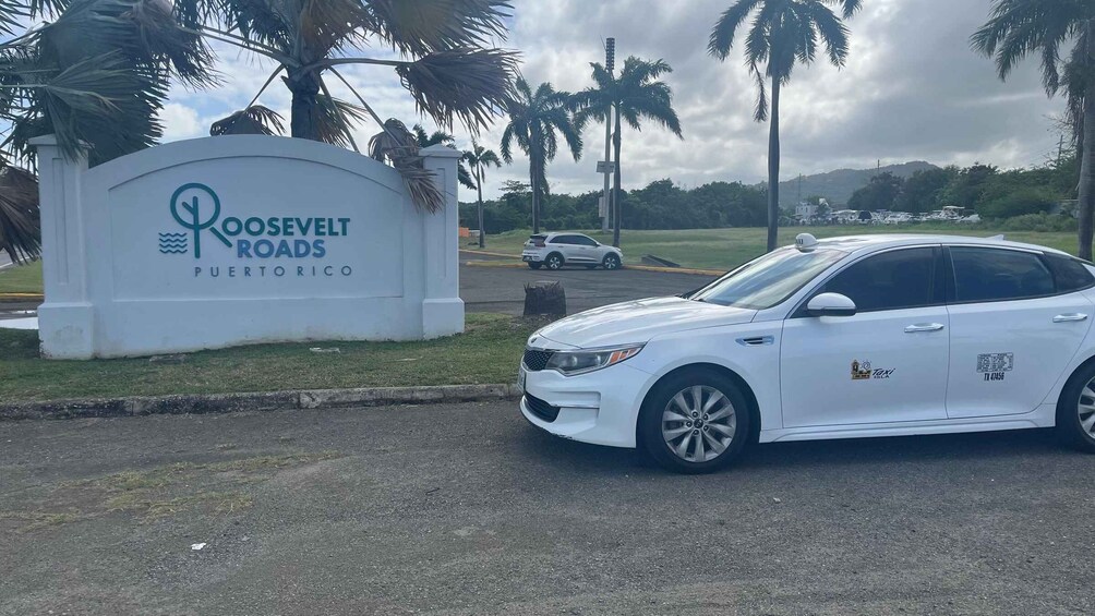 A white car parked in front of a sign for Roosevelt Roads, Puerto Rico. 2