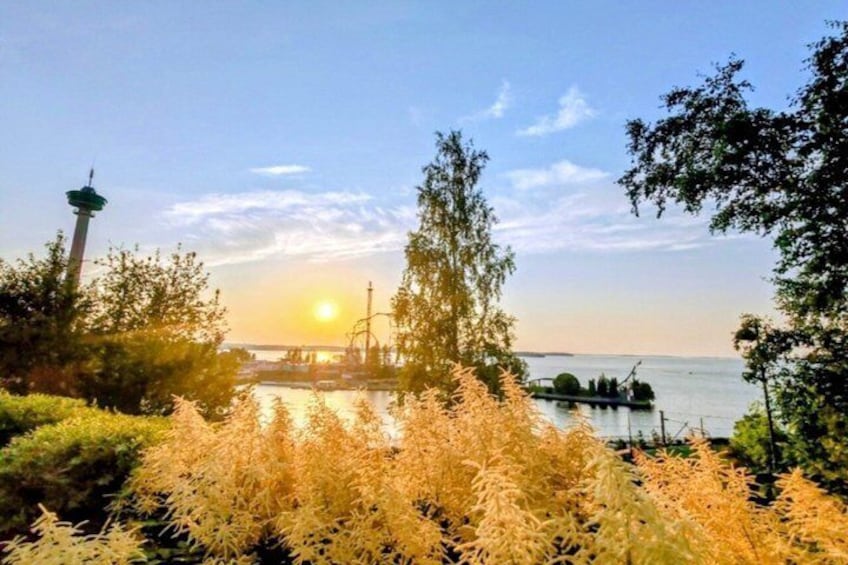 A sunset over a body of water with a tower and trees in the foreground. 4