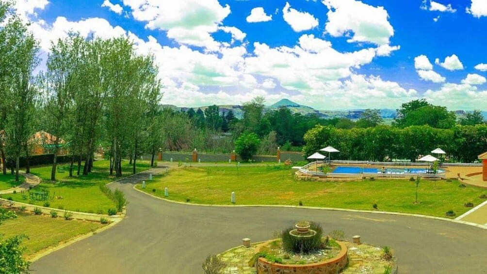 A park with a fountain, a swimming pool, and a road. 3