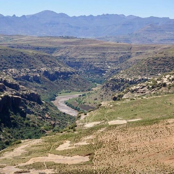 A mountainous landscape with a winding road, green vegetation, and distant hills. 2