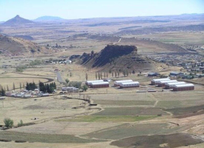 A rural landscape with a prominent hill, several buildings, and a winding road. 4
