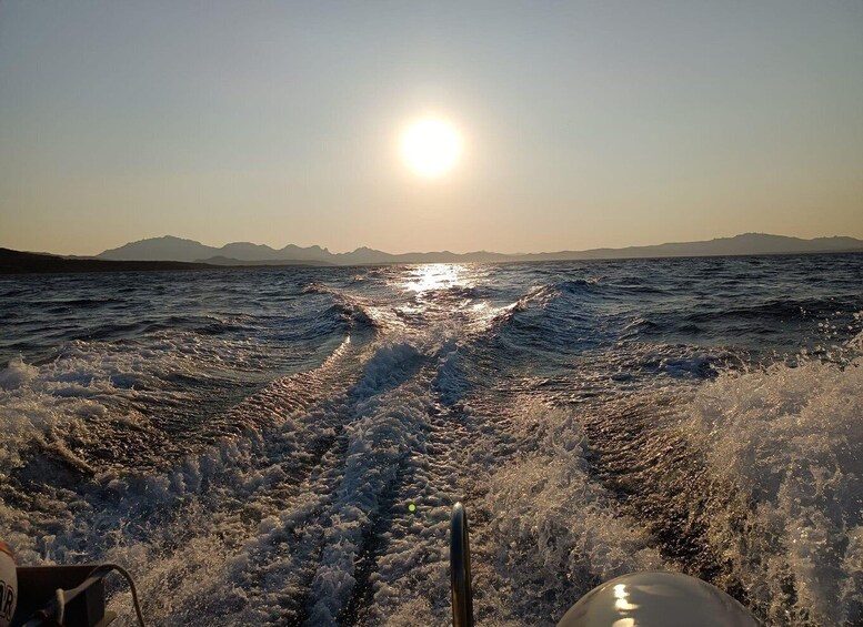 A boat's wake on a calm sea with the sun setting in the background. 5