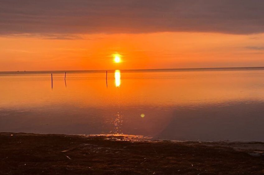 A sunset over a calm body of water with a clear horizon. 5