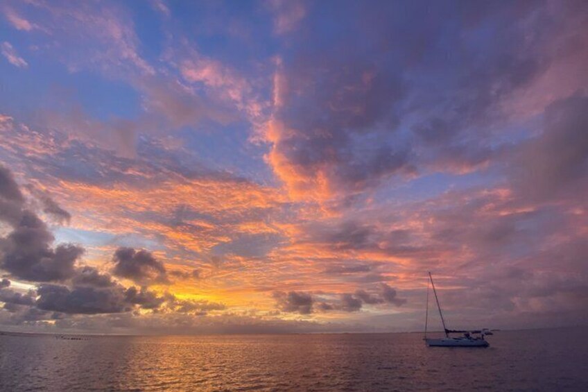 A sunset over a calm sea with a sailboat. 3