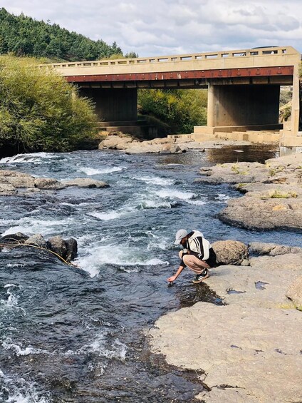 A river flowing under a bridge with a person crouching near the water. 2