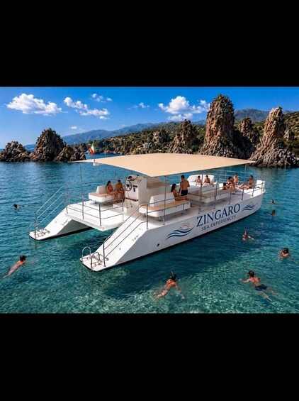 A white boat named ZINGARO with people swimming around it. 3