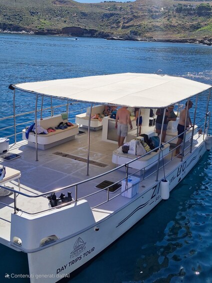A boat with a white deck and a covered seating area, named 'ZINGARO,' on a body of water with a hilly landscape in the background. 5