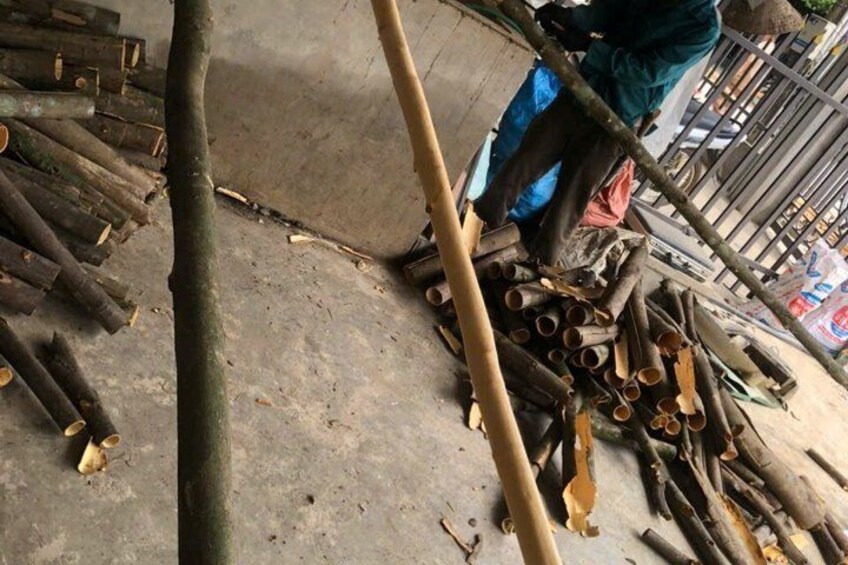 A person working with wooden logs and tubes, possibly in a workshop or construction site. 4