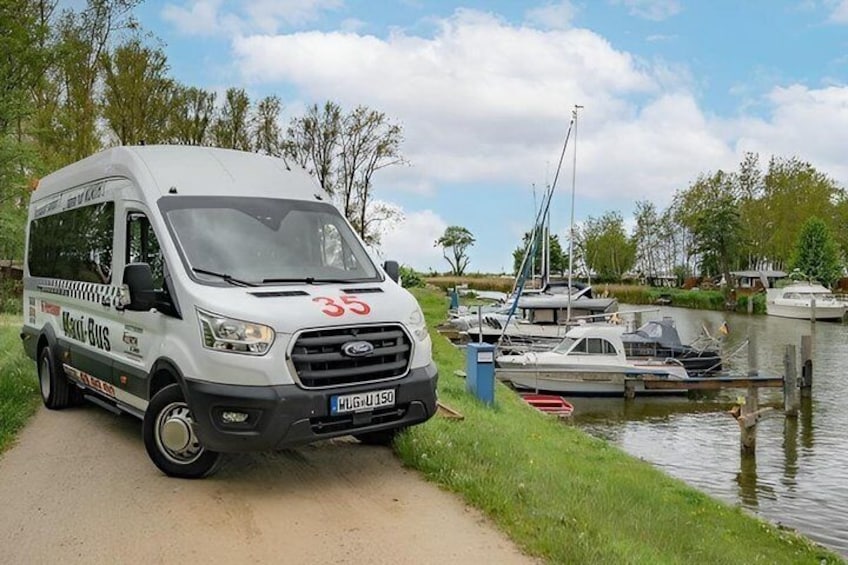 A white van with 'Daci-Bus' and the number '35' parked by a canal with boats. 2