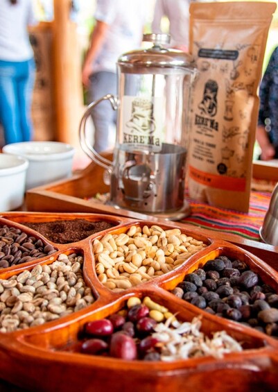 A coffee grinder, a bag of coffee, and various beans and nuts in wooden containers. 2