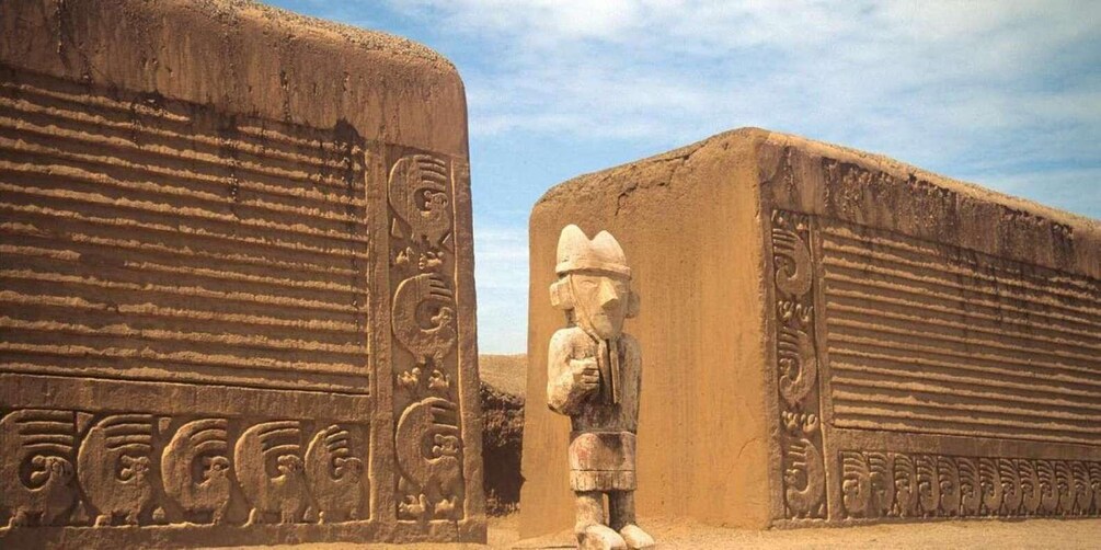 A stone statue in a desert landscape with ancient carvings on the walls. 3