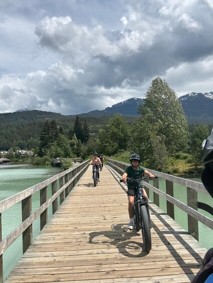 A wooden bridge over a river with cyclists riding on it. 5