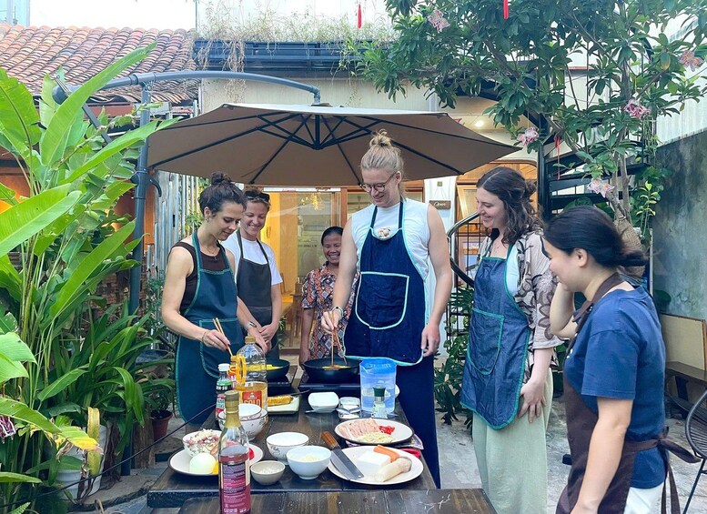 A group of people preparing food outdoors with a table full of ingredients and cooking utensils. 2